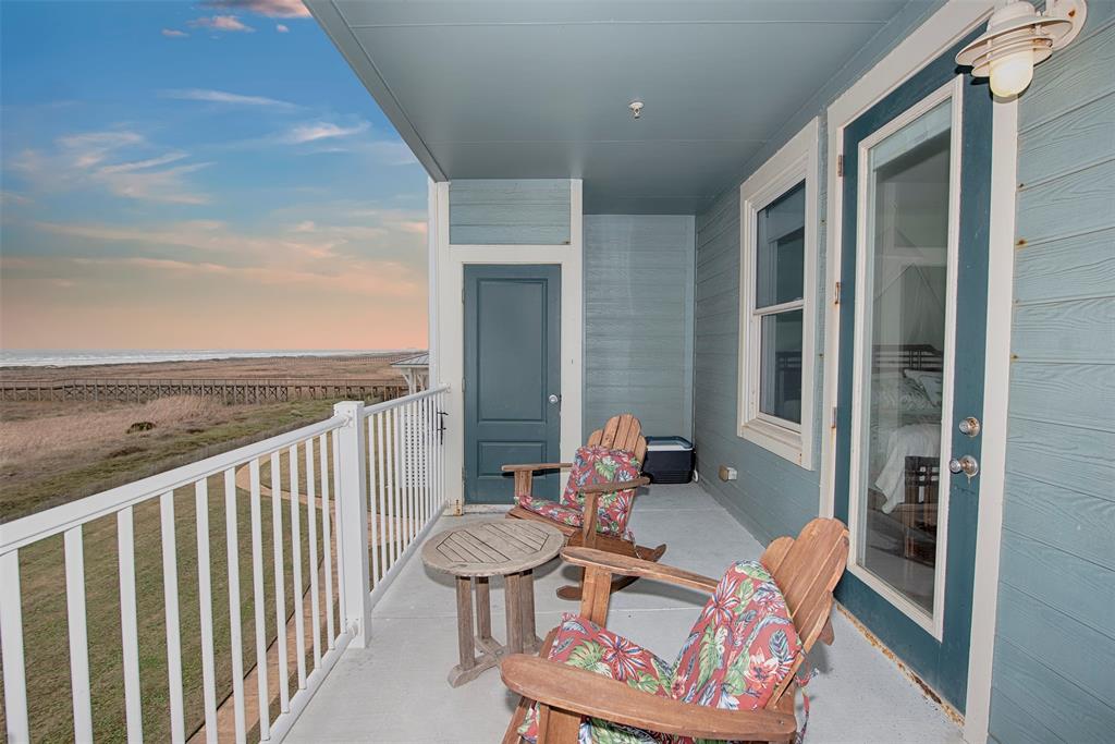 Adirondack chairs on balcony overlooking beach walkover at sunset